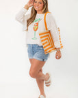 Elevate your style with the Show Me Your Mumu Ciao Cocktail Woodsy Sweater paired with striped orange tote and platform sandals.