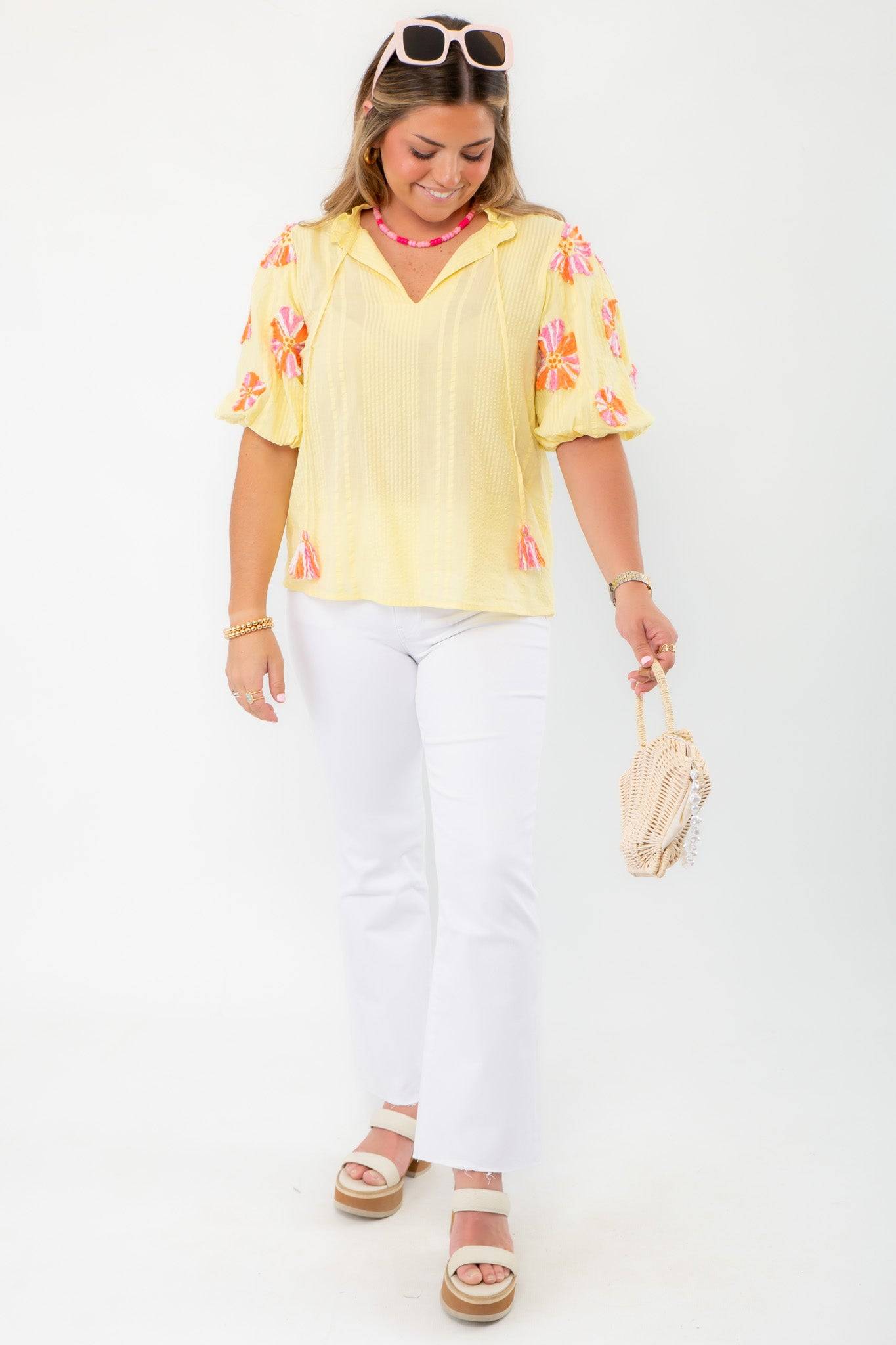 Model wearing THML Yellow Floral Pom Blouse paired with white jeans and platform sandals, ideal for a spring vacation outfit.
