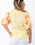 Rear angle of THML Yellow Floral Pom Blouse showcasing textured yellow fabric and embroidered floral puff sleeves for spring style.