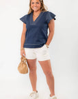 Sophisticated Nautical Charm: THML Navy Ruffle Sleeve Top styled with white shorts and sneakers, showcasing a casual summer outfit.