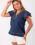 THML Navy Ruffle Sleeve Top with stitched detailing and V-neckline, paired with white shorts for a chic nautical-inspired look.