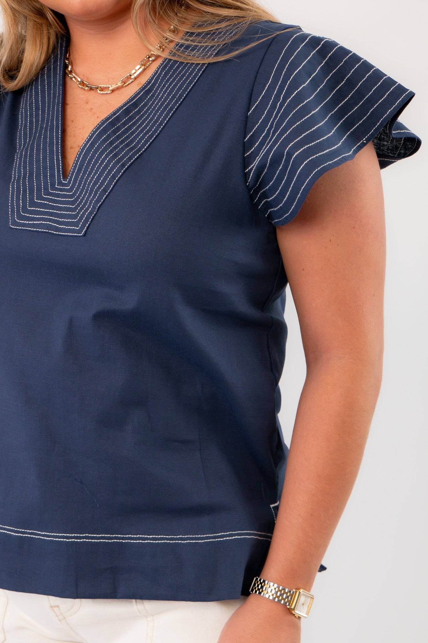Close-up of THML Navy Ruffle Sleeve Top highlighting intricate white stitching on sleeves and neckline for a refined finish.