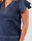 Close-up of THML Navy Ruffle Sleeve Top highlighting intricate white stitching on sleeves and neckline for a refined finish.