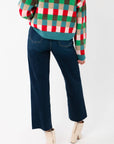 Close-up of the lower back of the Holiday Check Knit Sweater and dark denim jeans, highlighting the sweater’s festive check pattern.