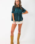 Model wearing Lacy Teal Velvet Babydoll Top with tan boots and cream skirt, showcasing festive lace and velvet design for winter fashion.