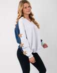 Side view of the Wrapped in Stars Sweatshirt showing navy sleeves with gold star patches, combining comfort and celestial style.