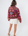 Back view of Chocolate Hearts Patterned Sweater showcasing detailed heart and diamond patterns in pink, red, and blue on a warm brown knit.