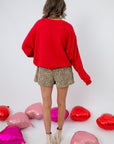 Back view of Lover Red Ribbed Sweater – Cozy Valentine’s Day Pullover showing ribbed texture and loose fit, styled with leopard shorts.