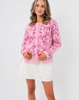 Something Sweeter Pink Jacquard Fringe Hem Cardigan with long sleeves, button front, and fringe detail, styled over a white mini skirt.