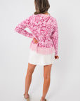 Back view of the Something Sweeter Pink Jacquard Fringe Hem Cardigan highlighting the jacquard pattern and fringe hem over a white skirt.