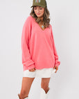 Show Me Your Mumu Coral Knit Anything Goes Sweater with oversized fit and v-neck, styled with white mini skirt and white boots.