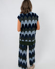 Back view of Retro Wave Metallic Knit Sleeveless Sweater with tunic length and scalloped wave pattern, styled with matching shimmer pants.