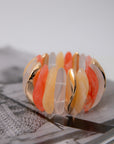 Orange Wide Stone Bracelet displayed on magazine, showcasing multi-color stones in orange, peach, and frosted tones with gold accents.