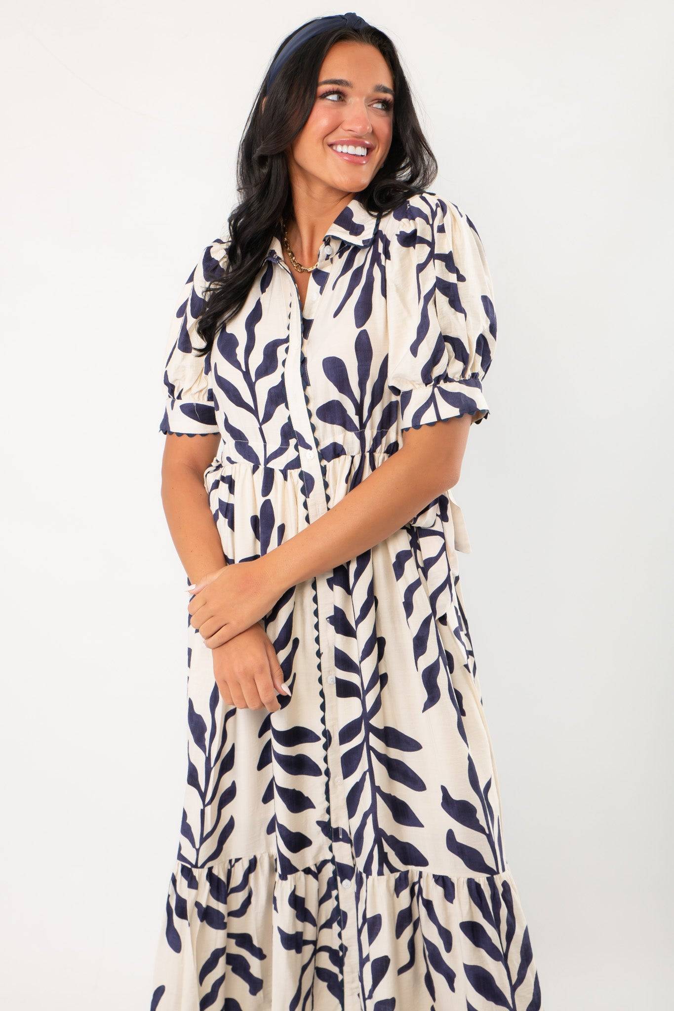 Close-up of Harmony Navy & Cream Puff Sleeve Collared Midi Dress showing puff sleeves, collared neckline, and navy leaf pattern on cream fabric.