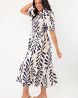 Side view of Harmony Navy & Cream Puff Sleeve Collared Midi Dress highlighting flowy fit, puff sleeves, and navy leaf print on cream background.