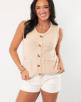 Taupe knit vest with front button-down design and patch pockets, styled as a sleeveless summer sweater vest for women.