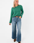 Full front view of Z Supply Botanical Green Emerson Sweater styled with flared jeans and boots, perfect for a relaxed bohemian outfit.