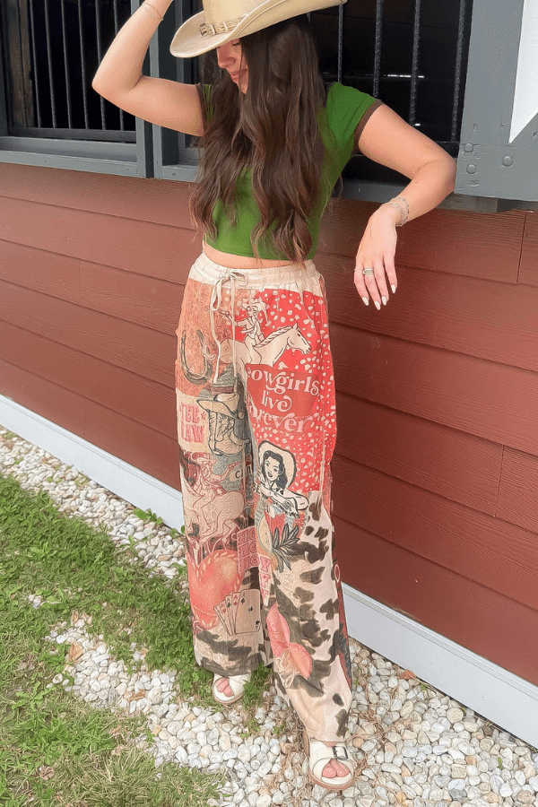 Ori Howdy Drawstring Pants in western print with elastic waist, styled with green top and cowboy hat for a rustic outdoor look.