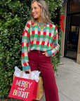 Holiday Check Knit Sweater in festive blue, red, and green worn with burgundy pants, styled for a cheerful Christmas outing.