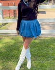 Denim Bubble Skort - Mini Skort styled with white boots and black top, featuring high waist and bubble hem for a chic fall look.