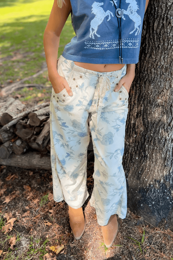 Weston Cream Floral Jeans with mid-rise fit and relaxed barrel leg, styled outdoors with tan boots and a cropped graphic tank.