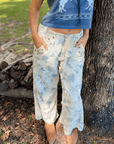 Weston Cream Floral Jeans with mid-rise fit and relaxed barrel leg, styled outdoors with tan boots and a cropped graphic tank.