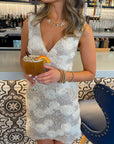 Champagne Rose Sequin Mini Dress with white floral appliqués and silver sequins, styled for a holiday party at a modern bar setting.