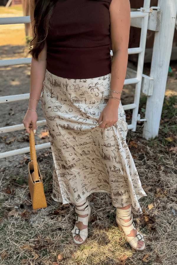 Old West Satin Maxi Skirt styled with a ribbed top and woven handbag, highlighting the flowy satin fabric and western-themed print in a fall setting.
