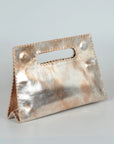 A metallic rose gold leather handbag with a top handle cutout, standing upright on a light gray background.