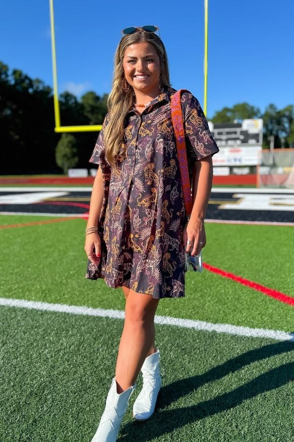 Model wearing Tiger Printed Button Down Mini Dress – Gameday Shirt Dress with a stadium backdrop, showcasing its relaxed fit and playful print.