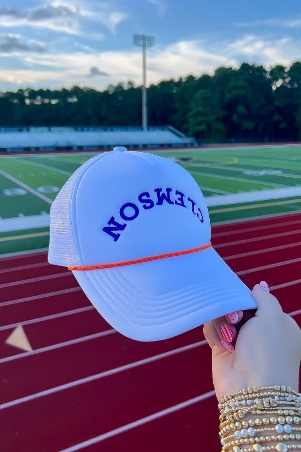 Clemson White Mesh Back Trucker Hat featuring breathable mesh, snapback fit, and upside-down Clemson text, perfect for sporty outdoor events.