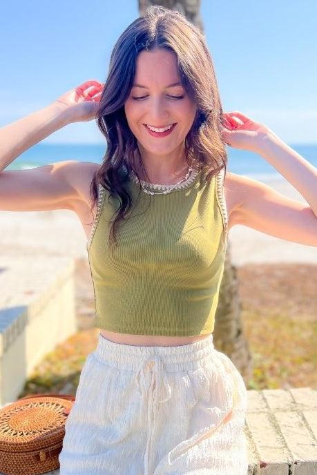 Chic Andie Green Stitched Crop Tank Top styled for a beachside look, featuring a lightweight rib knit fabric and intricate contrast stitch details.