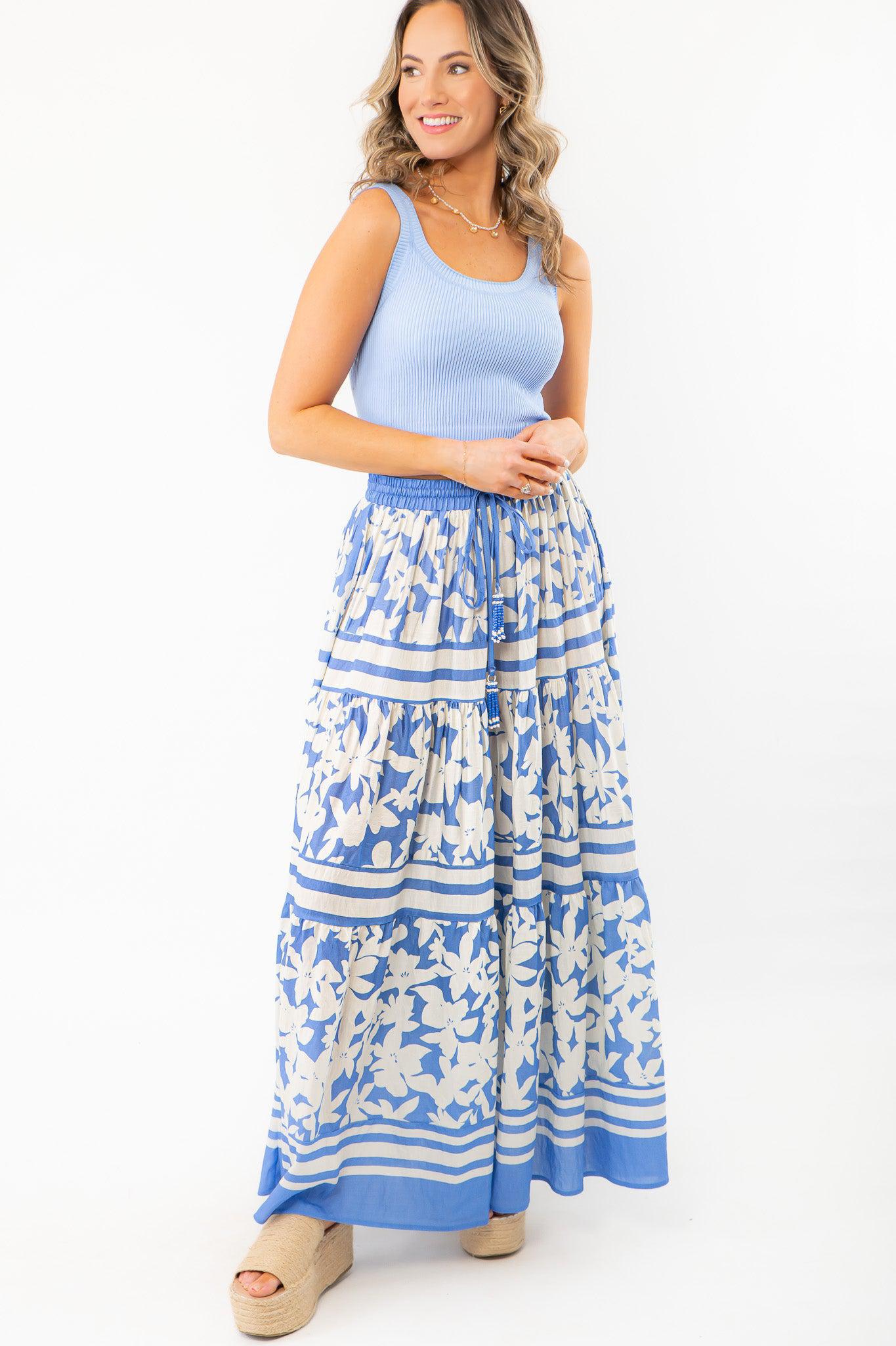 Elegant bright blue floral print tiered maxi skirt styled with a fitted blue tank top, ideal for beach outings and casual summer days.