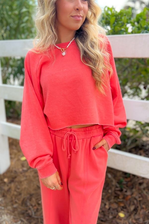 Close-up of Coral Feeling Wide Leg Sweatpants featuring a relaxed fit, drawstring waist, and raw hem, styled with a matching cropped sweatshirt.