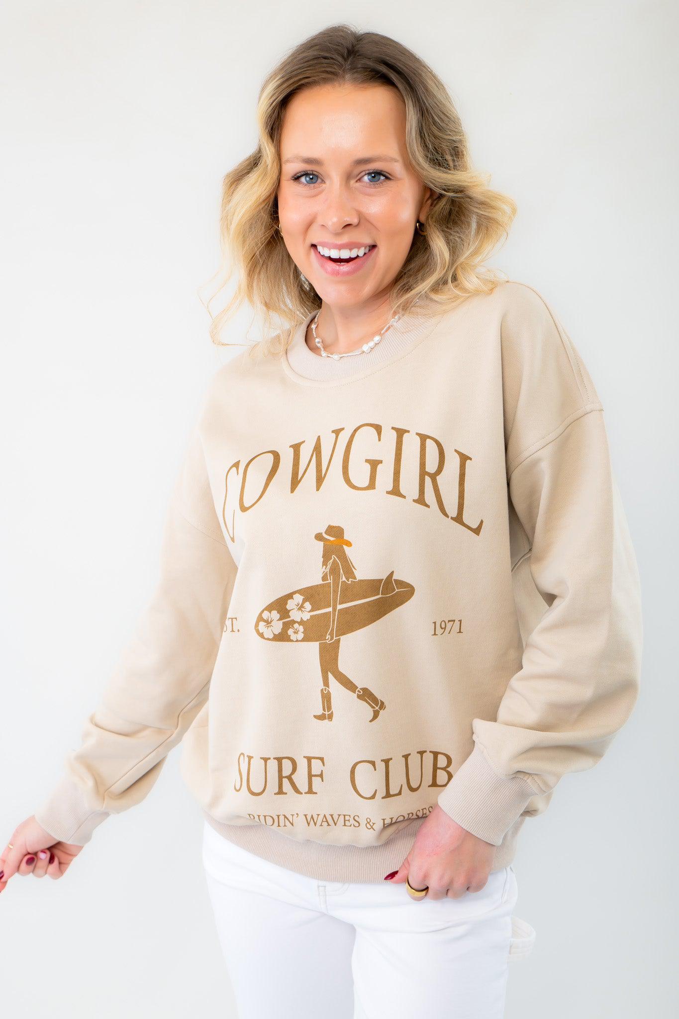 Cowgirl Surf Club Graphic Sweatshirt in taupe with a vintage-inspired design. Features a relaxed fit, crew neckline, and long sleeves for effortless summer style.