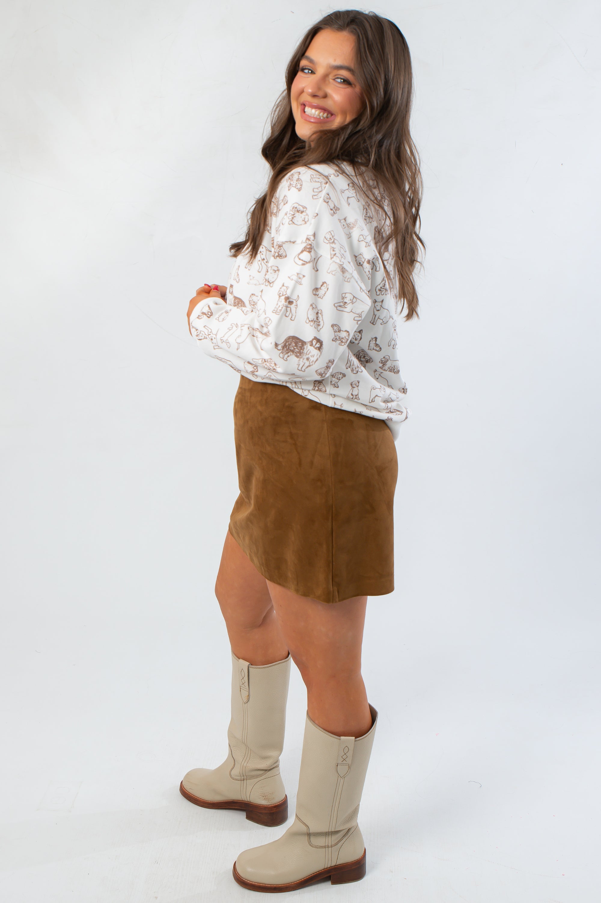 Side view of Snuggle Pup Dog Print Sweatshirt showing relaxed fit and playful dog pattern, styled with a brown skirt and cream boots.