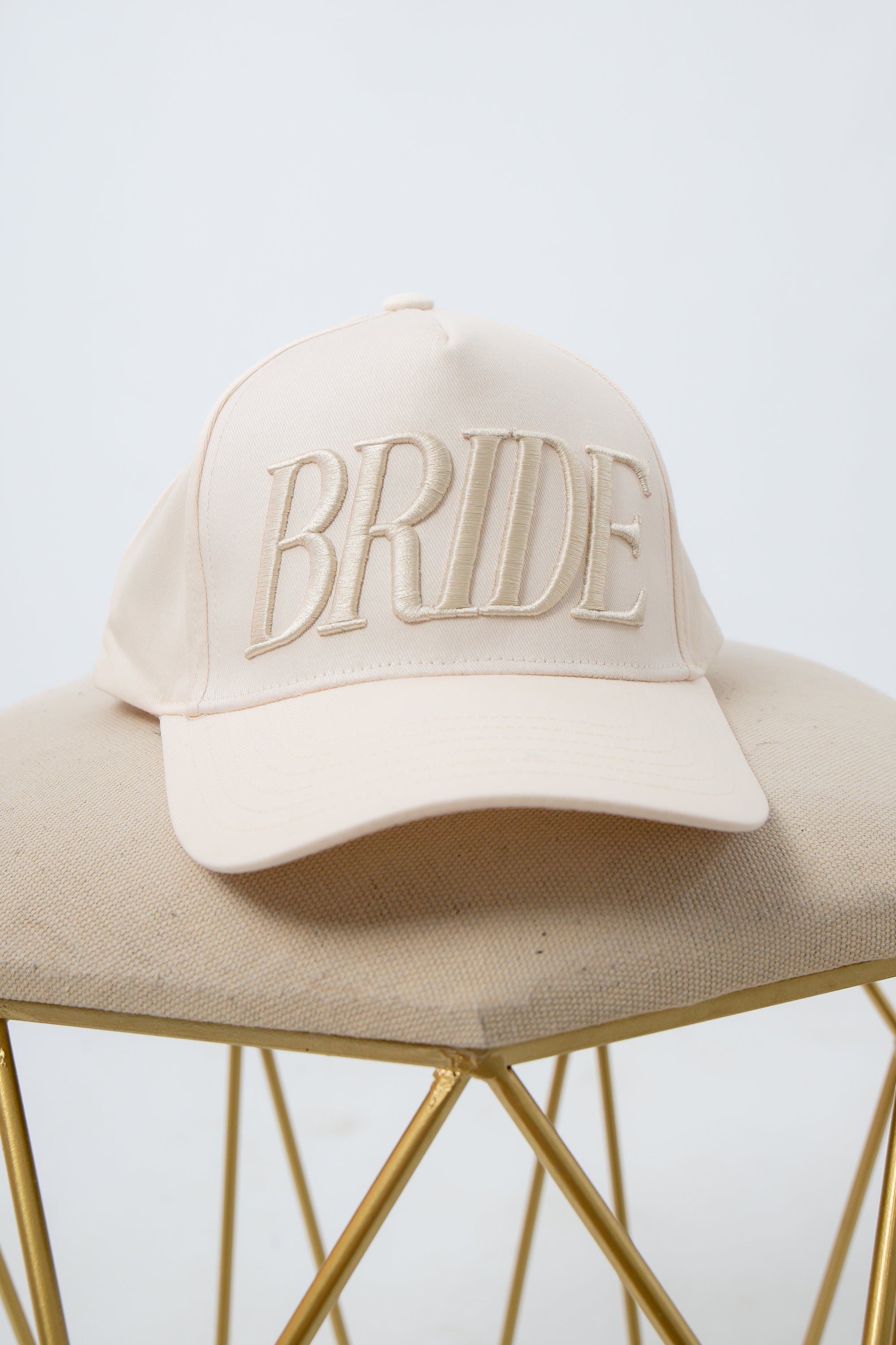 Beige Bride Embroidered Trucker Hat on beige fabric surface for bridal accessories