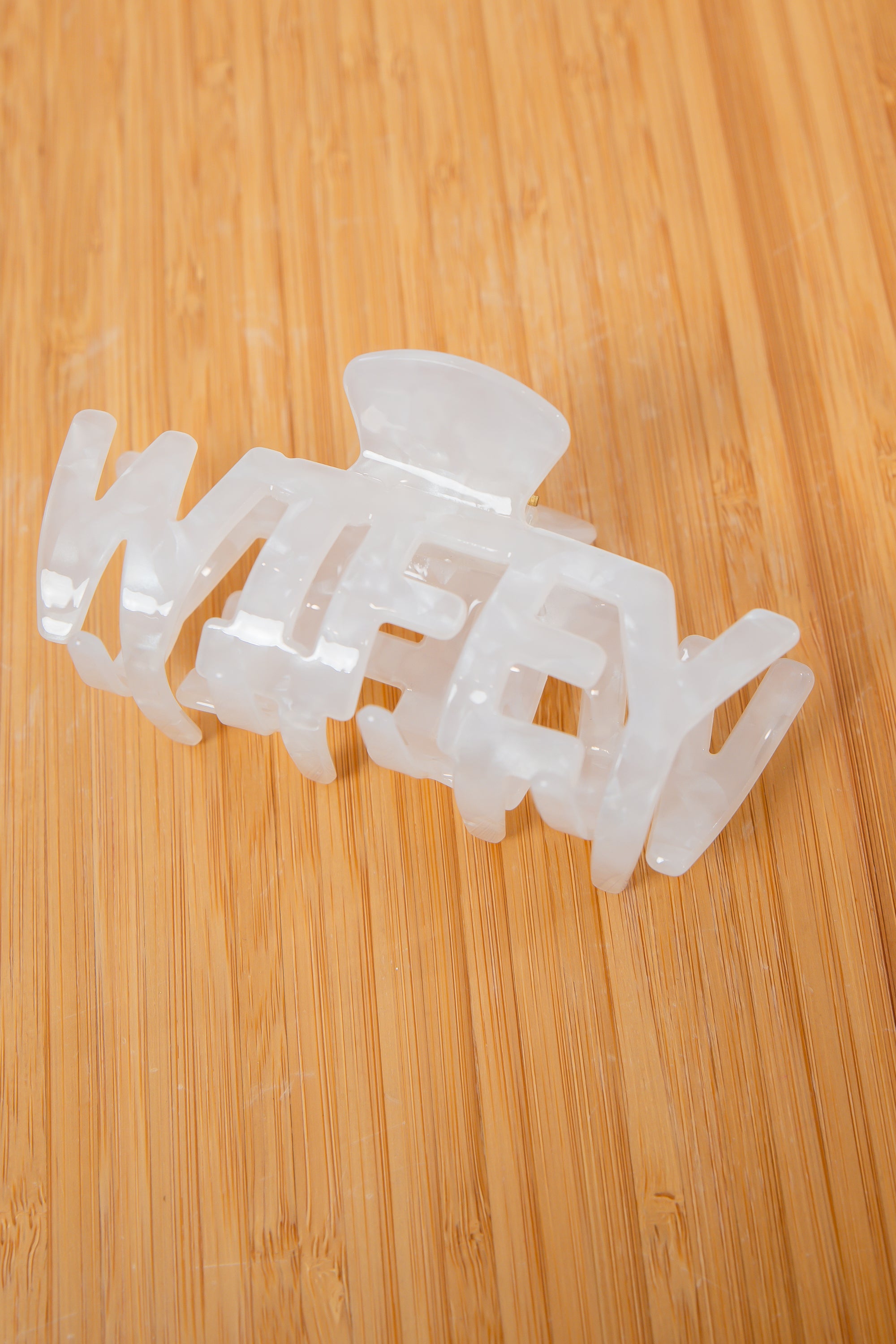 White acrylic Wifey Bridal Claw Clip on wooden surface