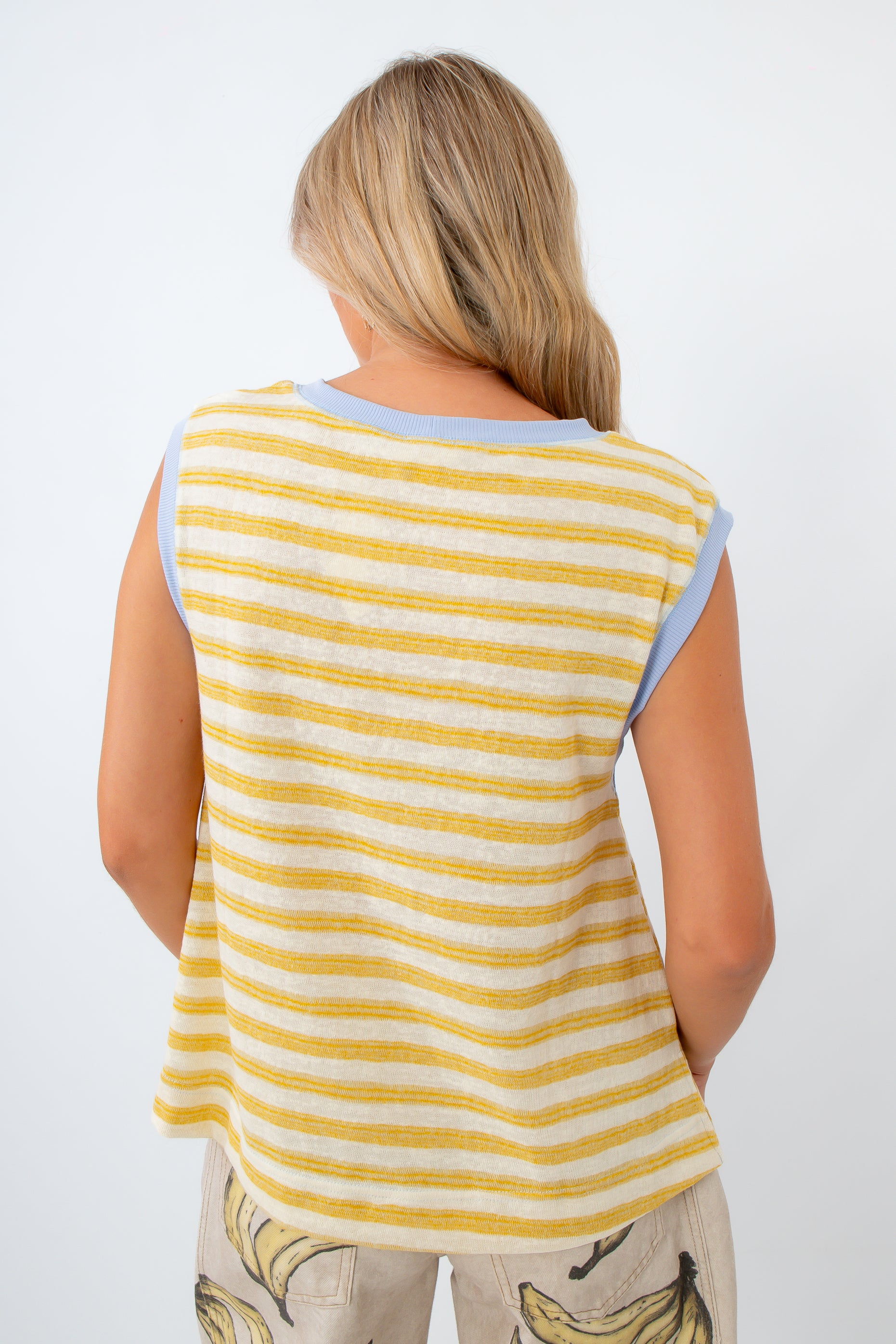 Woman wearing a yellow and white striped sleeveless top on a white background