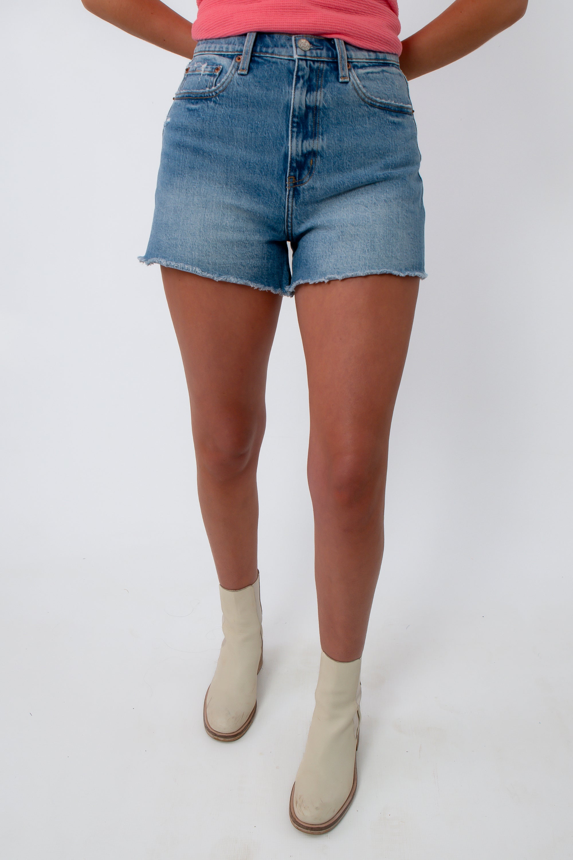 Close-up of denim shorts with frayed hem and high-rise fit