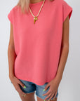 Woman wearing pink coral knit top, denim shorts, summer casual outfit