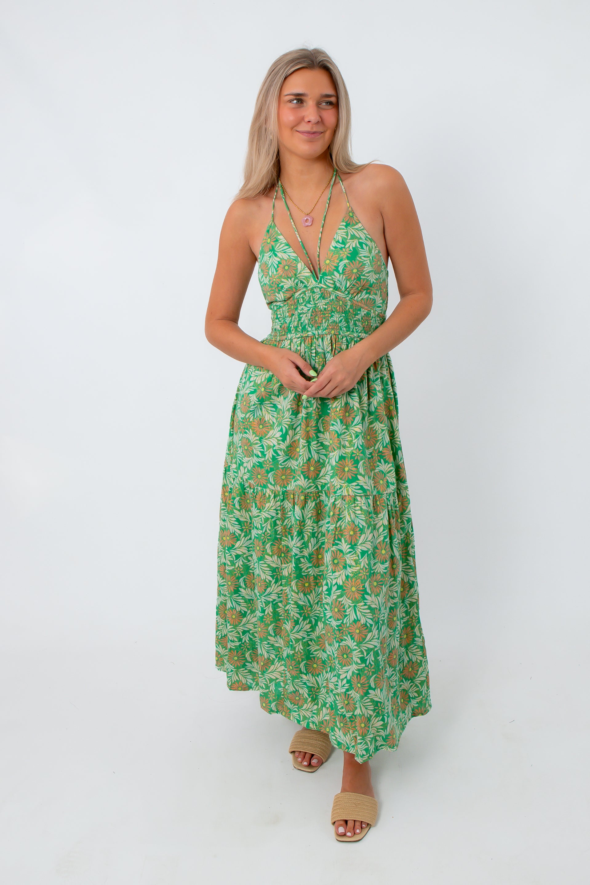 Model wearing green and orange floral maxi dress with layered necklaces, ideal for wedding guest attire