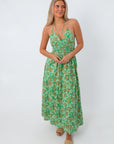Model wearing green and orange floral maxi dress with layered necklaces, ideal for wedding guest attire