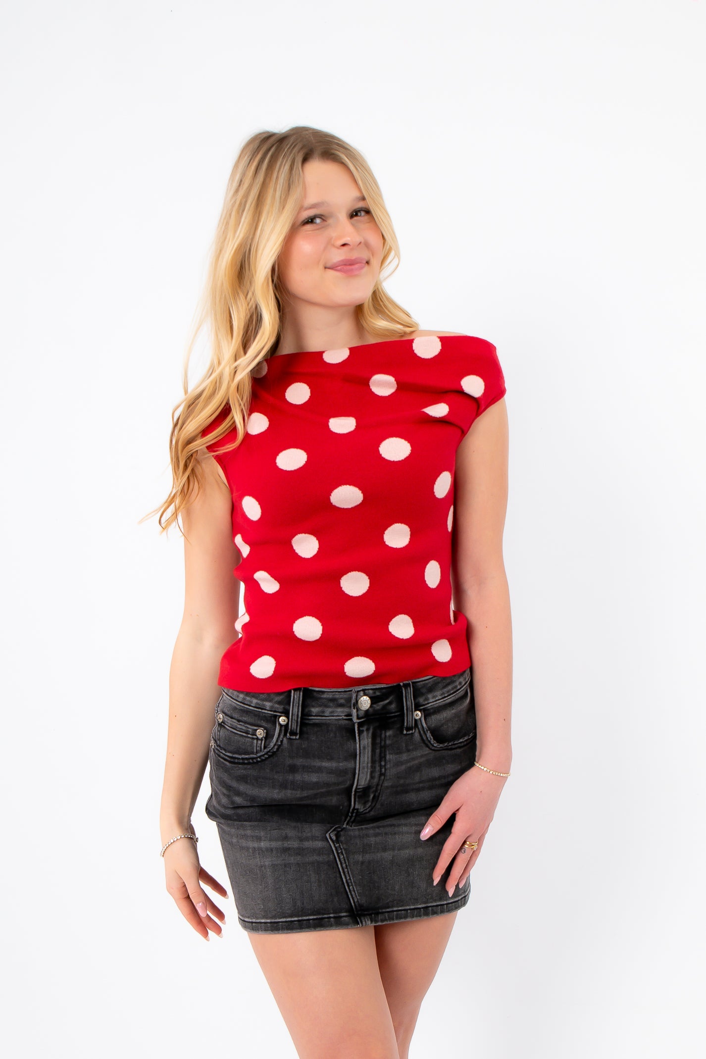 Retro Romance Red Polka Dot Asymmetrical Top styled with a black denim mini skirt. Features bold white polka dots and a fitted silhouette.