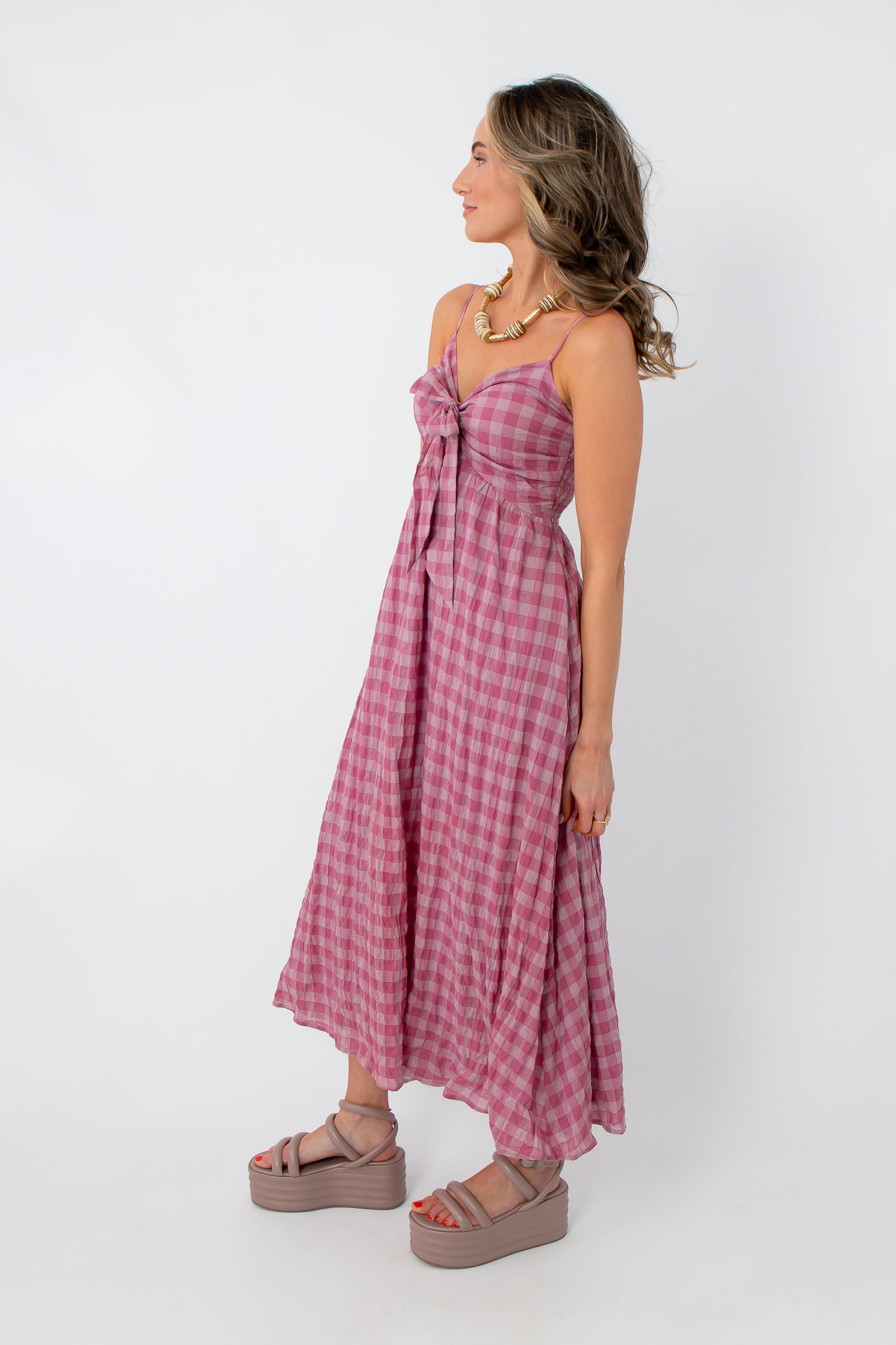 Pink gingham midi dress with spaghetti straps and front tie detail, styled for spring and summer occasions