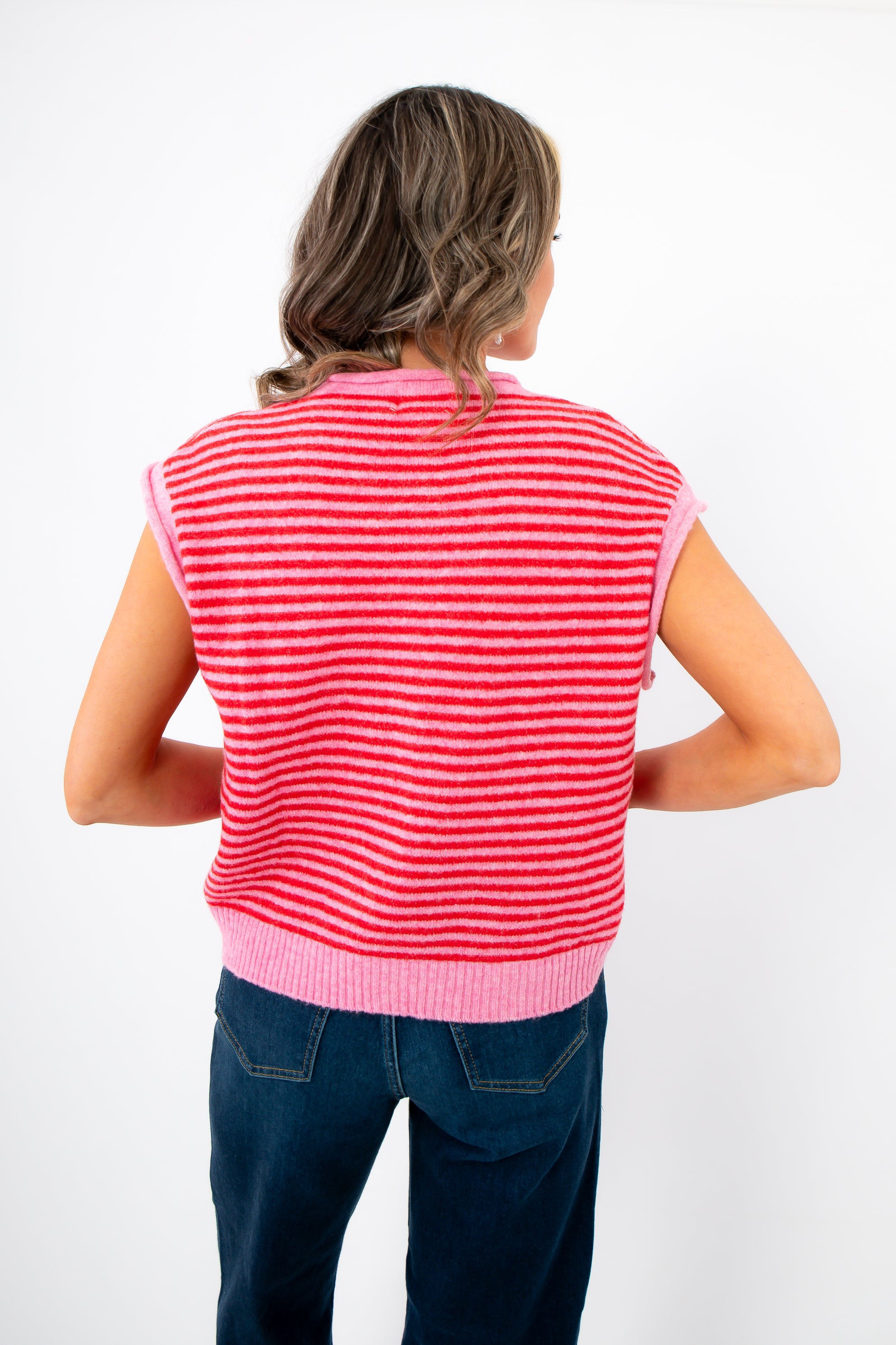 Back view of Piper Pink Stripe Short Sleeve Cardigan showing horizontal pink and red stripes and ribbed waistband for a cozy spring look.