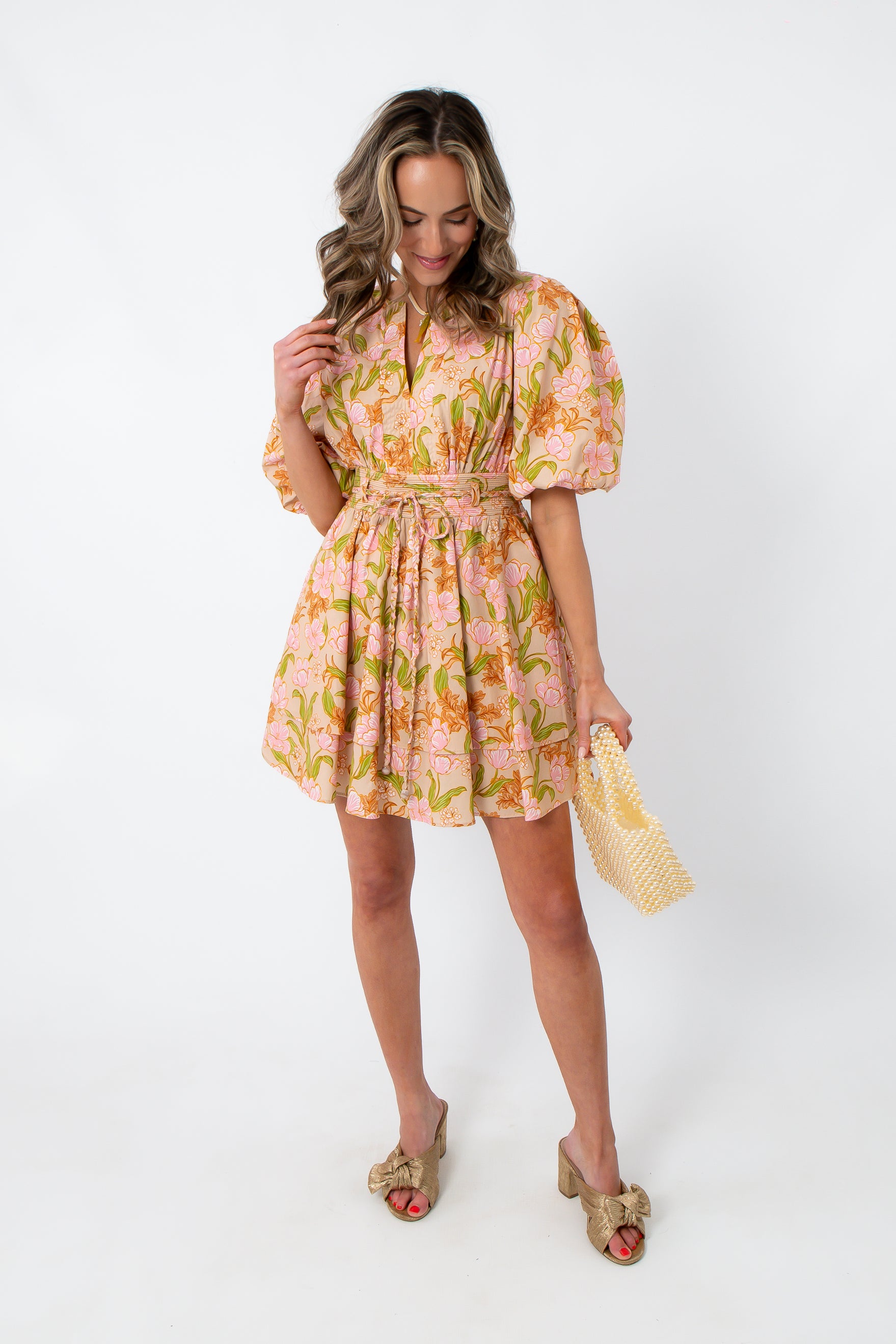 Pink and orange floral mini dress with puff sleeves, styled with beige bow heels and pearl handbag