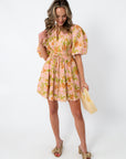 Pink and orange floral mini dress with puff sleeves, styled with beige bow heels and pearl handbag