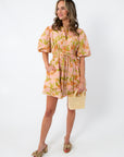 Pink and orange floral mini dress with puff sleeves, styled with beige bow heels and pearl handbag