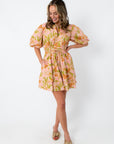 Pink and orange floral mini dress with puff sleeves, styled with beige bow heels and pearl handbag
